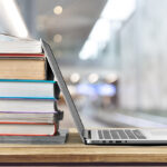 UltimateDevSolutions Learning with Stack of books with laptop on wooden table